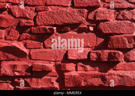Closeup of the exterior stone wall of a building painted in red. Stock Photo
