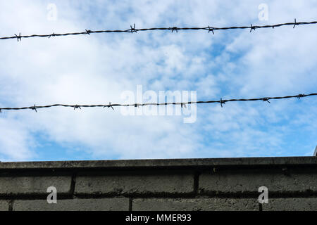 Barbed wire fence against the blue sky with clouds Stock Photo