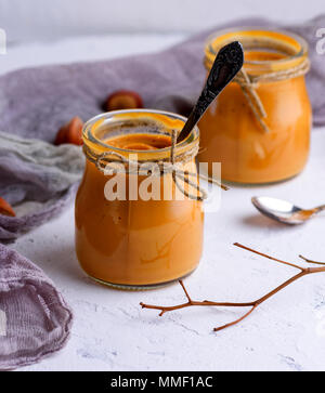 Caramel dessert Toffee in a glass jar on a white texture table, close up Stock Photo