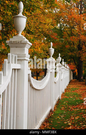 A white picket fence contrasts against the colorful autumn leaves in Vermont Stock Photo