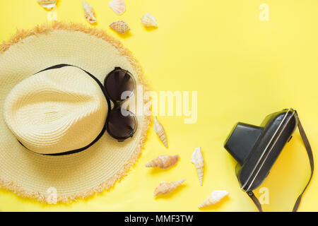 Straw beach foman's hat, black sun glasses with retro camera on yellow background. Top view. Flat lay. Space for text. Travel concept. Stock Photo