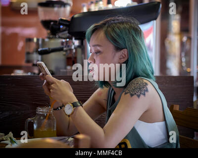 Woman with smartphone, close up. Female with green hair and shoulder tattoo. Stock Photo