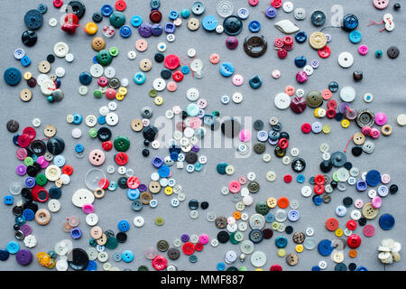 top view of scattered colorful buttons on grey cloth background Stock Photo