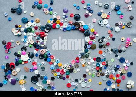 top view of colorful buttons heart shaped frame on grey cloth background Stock Photo