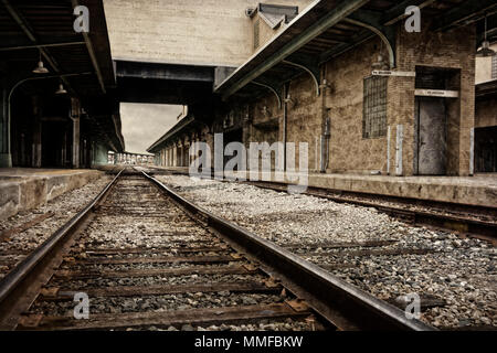 Looking down the rustic ruins of railroad tracks of an old train station depot processed in a sepia tone. Stock Photo