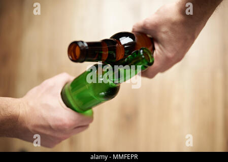 Cheers with beer bottles. Hand hold beers close-up above view Stock Photo