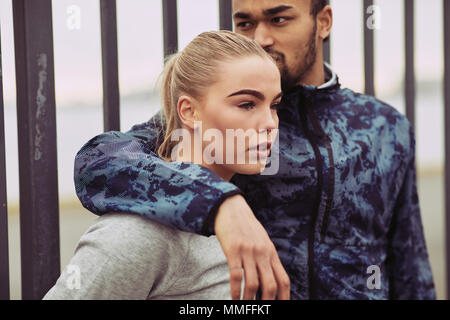 Young man in sportswear standing with his arm around his girlfriend while taking a break together from a run Stock Photo