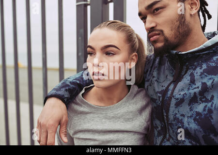 Young man in sportswear standing outside with his arm around his girlfriend while taking a break from a run together Stock Photo