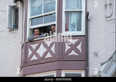 Windsor, UK.  11 May 2018.  Men look from a window at a wedding taking place below them as preparations continue in Windsor for the wedding between Prince Harry and Meghan Markle on 19 May.  Thousands of people are expected to visit the town for what has been billed as the wedding of the year.  Credit: Stephen Chung / Alamy Live News Stock Photo