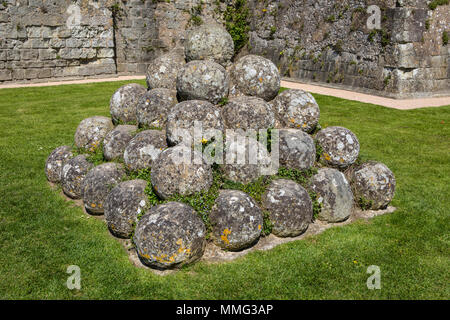 Old cannon balls inside the historic ruin of Pevensey Castle in East Sussex, UK.  It is a medieval castle and former Roman Saxon Shore fort. Stock Photo