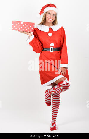 Blonde woman in Santa Claus clothes smiling with gift box in her hands. Young female with blue eyes wearing striped socks, isolated on white Stock Photo