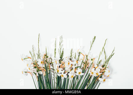 Bouquet of beautiful narcissus with green spikelets on white background. Stylish floral composition with copy space. Stock Photo