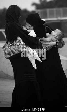 Two Saudi women holding and kissing their babies in Jeddah, Saudi Arabia Stock Photo