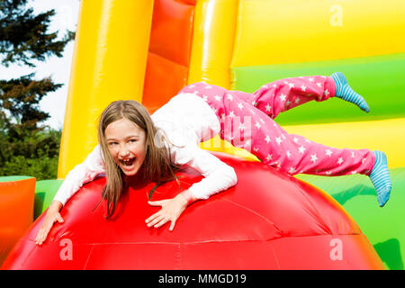 Happy little girl having lots of fun on a inflate castle while jumping. Stock Photo