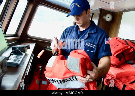 U.S. Coast Guard Marine Safety Detachment American Samoa is a field unit responsible for commercial fishing vessel safety inspections and regulatory compliance. The archival image documents a marine science technician conducting a lifejacket serviceability check aboard the 190-foot U.S.-flagged tuna purse seiner Raffaello on October 23, 2017, during a post-fire repair deficiency inspection. Stock Photo