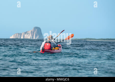 Sea kayaking off San Cristobal Island with Kicker Rock in the background, Galapagos Islands, Ecuador. Stock Photo