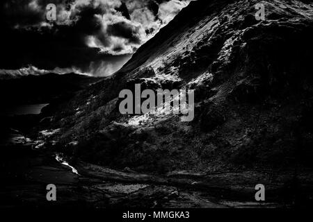 Dark and moody black and white photo of dappled light on the Eastern side of Mount Snowdon on a summer's day Stock Photo