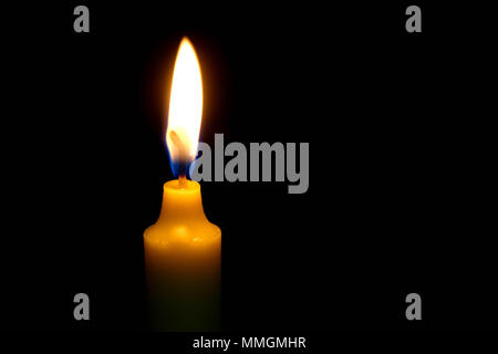 One light candle burning brightly on black background. Stock Photo