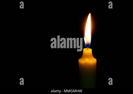 One light candle burning brightly on black background. Stock Photo