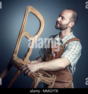 portrait of carpente holding unfinished chair studio shot Stock Photo