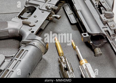 A disassembled AR15 rifle laying on a table with a 22 mm cartridge adaptor and a 5.56mm bullet Stock Photo