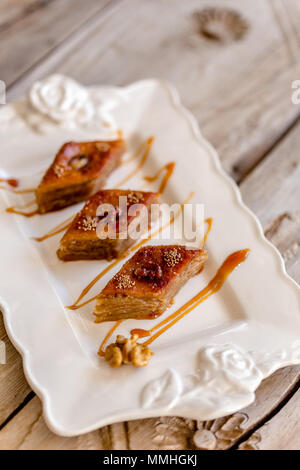 Azerbaijani traditional baklava in white ceramic plate over rustic wooden tabletop.  Selective focus. Stock Photo