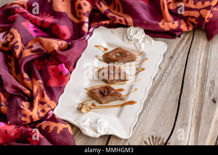 Azerbaijani traditional baklava in white ceramic plate over rustic wooden tabletop.  Selective focus. Stock Photo