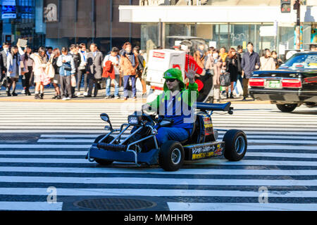 Tokyo, Shibuya crossing. Popular tourist activity, driving MariCar, Mario kart while dressed as Mario character. Man waving while driving. Stock Photo