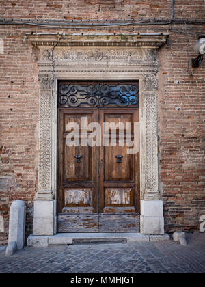 Old wooden portal with columns and architrave in white stone carved with floral motifs. Stock Photo