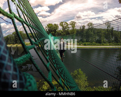 Young girl climbs on a high ropes course Stock Photo