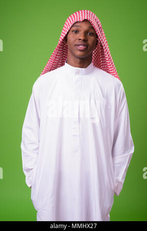 Young African man wearing traditional Muslim clothes against gre Stock Photo