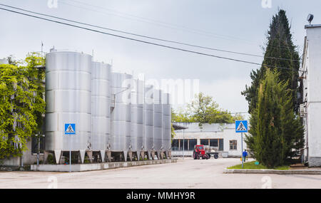 Shiny steel tanks stand in a row along empty street, modern wine factory equipment Stock Photo