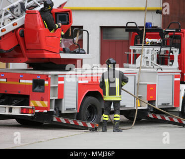 big red fire engine with aerial ladder and firefighters during an emergency Stock Photo