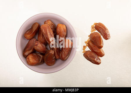 Dried dates on bowl and branch of dried dates on white background , top view Stock Photo