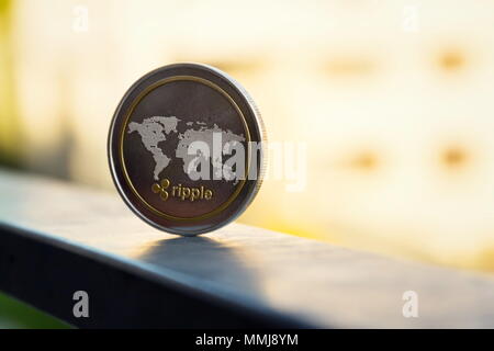 Silver gold ripple coin lying on handrail, cryptocurrency investing concept Stock Photo