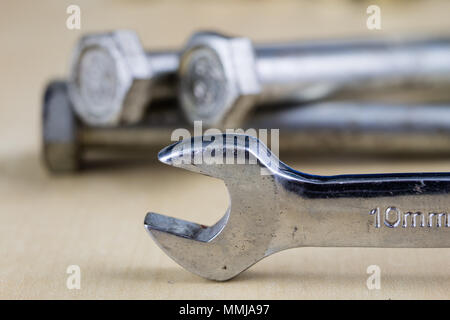 Metric screw and key on a wooden table. Mechanical accessories in the locksmith workshop. Light background. Stock Photo