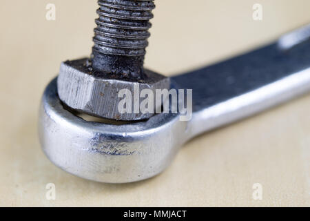 Metric screw and key on a wooden table. Mechanical accessories in the locksmith workshop. Light background. Stock Photo