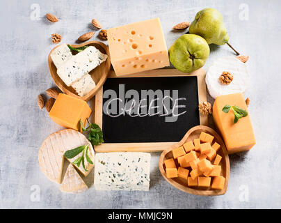 Different kinds of cheeses on rustic wooden board.