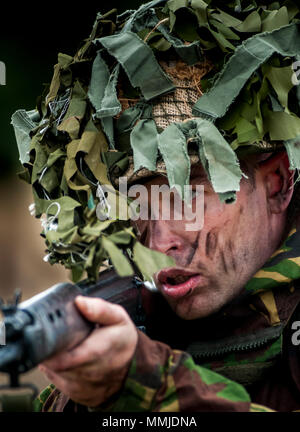 Portrait of 1970 – 1980 British Army soldier in camouflage suit and steel helmet carrying a SLR (Self-Loading Rifle) L1A1 - calibre of 7.62 mm (Posed by Model) Stock Photo