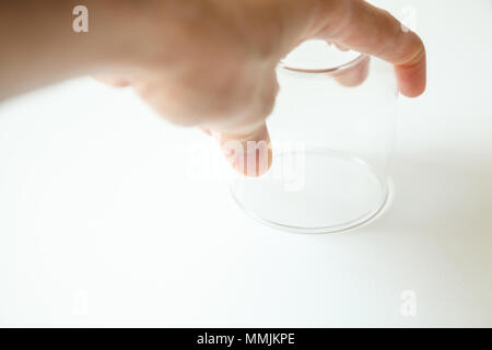hand hold glass upside down on white background Stock Photo