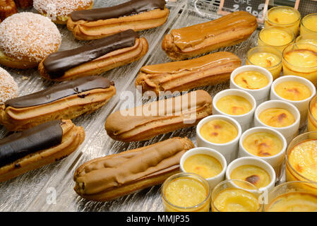 Display of Chocolate Eclairs, Coffee Eclairs and Crèmes Caramels &  Pastries or Cakes in a French Patisserie France Stock Photo