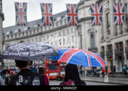 London, UK. 12 May 2018.  UK Weather - A tourist carries an umbrella decorated with the Union flag as Union flags above decorate Regent Street ahead of the Royal wedding of Prince Harry and Meghan Markle taking place on 19 May 2018.  Credit: Stephen Chung / Alamy Live News Stock Photo