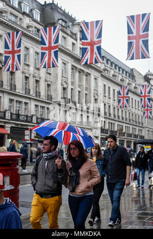 London, UK. 12 May 2018.  UK Weather - A tourist carries an umbrella decorated with the Union flag as Union flags above decorate Regent Street ahead of the Royal wedding of Prince Harry and Meghan Markle taking place on 19 May 2018.  Credit: Stephen Chung / Alamy Live News Stock Photo
