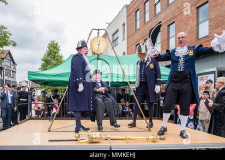 Saturday May 12th 2018. High Wycombe, Buckinghamshire, England, GB, UK. The quaint local tradition of 'Weighing in the Mayor' took place in the town centre today.  Traditionally, the outgoing and incoming mayor and civic officials are weighed at the beginning of the mayor's term of office each year to ascertain if they have gained weight at the expense of the taxpayer. The outgoing mayor, Brian Pearce is shown on the scales. Credit: D. Callcut/Alamy Live News Stock Photo