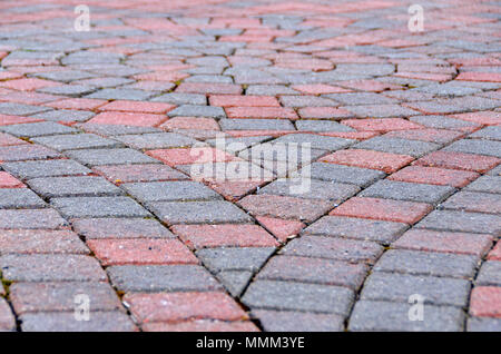 An abstract closeup photograph of a brick pavement. The sallow depth of field photo shows rectangular bricks fanning out to meet the circular centre. Stock Photo