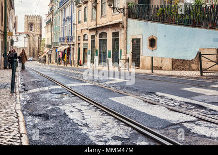 1 March 2018: Lisbon Portugal - Road with tram track in poor condition in the Alfama District. Lisbon Cathedral in the background. Stock Photo