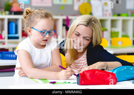 At school - beautiful teacher helps her student to learn Stock Photo