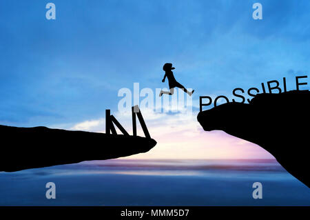 silhouette people jumping over the rock frome word impossible to possible Stock Photo
