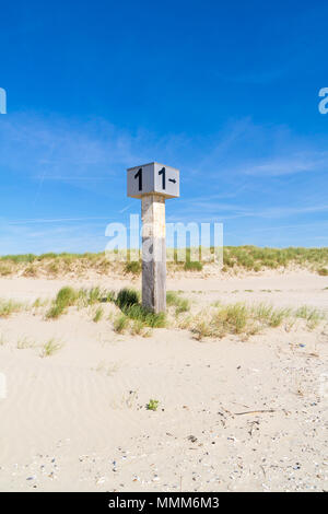 Marked beach pole with number 1 in sand on dune with marram grass on Kennemerstrand beach in IJmuiden, Noord-Holland, Netherlands Marked beach pole with number 1 in sand on dune with marram grass on Kennemerstrand beach in IJmuiden, Noord-Holland, Netherlands