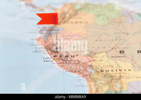 Small red flag marking the South American country of Peru on a world map. Stock Photo